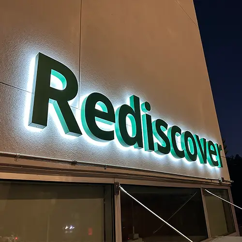 Backlit channel letter sign installed on exterior building wall at night, Culver City CA